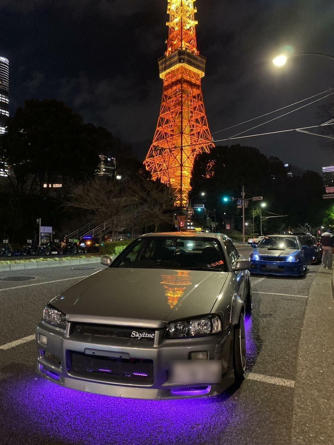 Guests standing with Tokyo Tower and car at night
